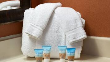 A bathroom with a white towel, a mirror, and three Aqua moisturizing lotion tubes.
