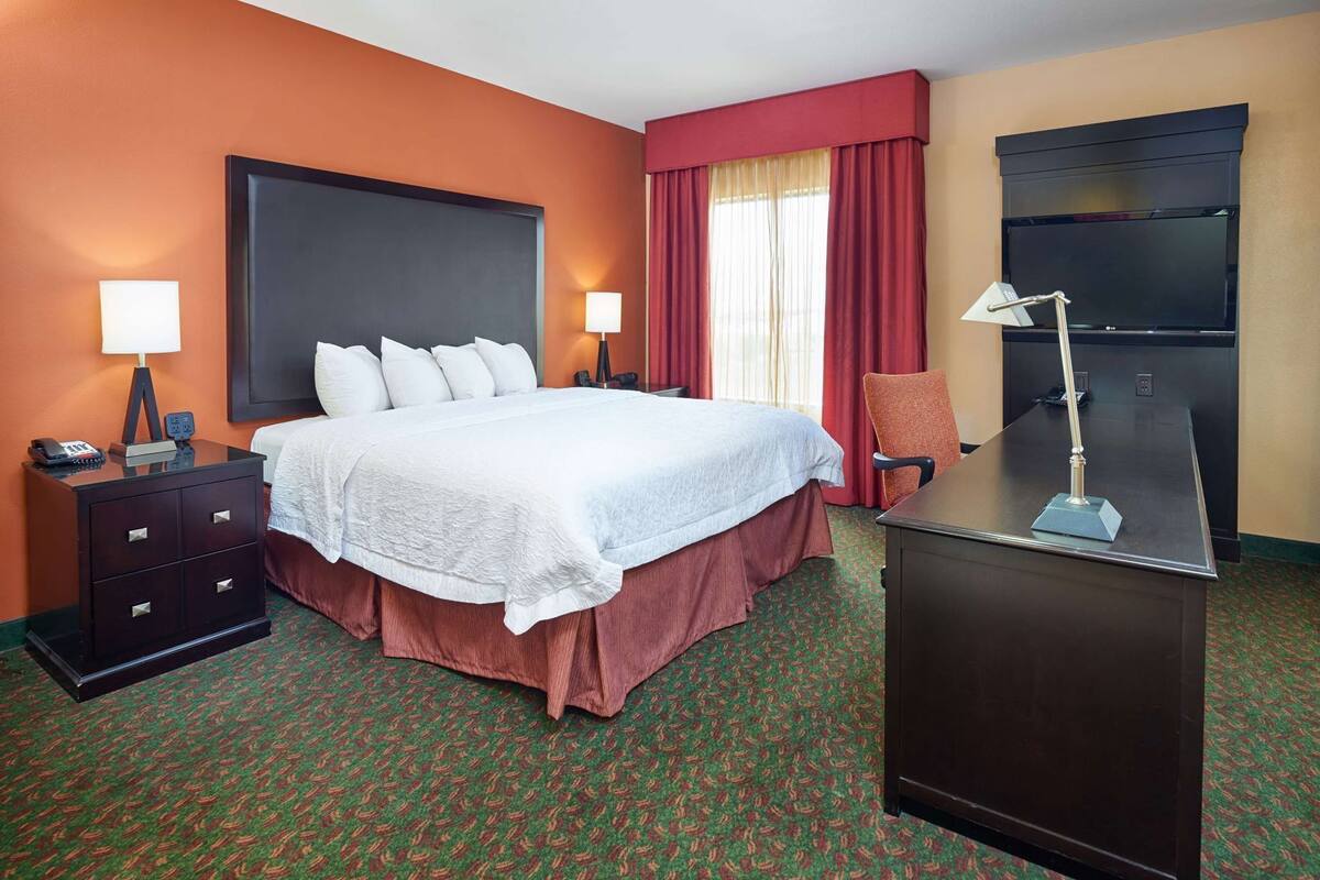 Une chambre d’hôtel équipée d’un lit, d’un bureau, d’une chaise, d’une télévision et d’un téléphone.