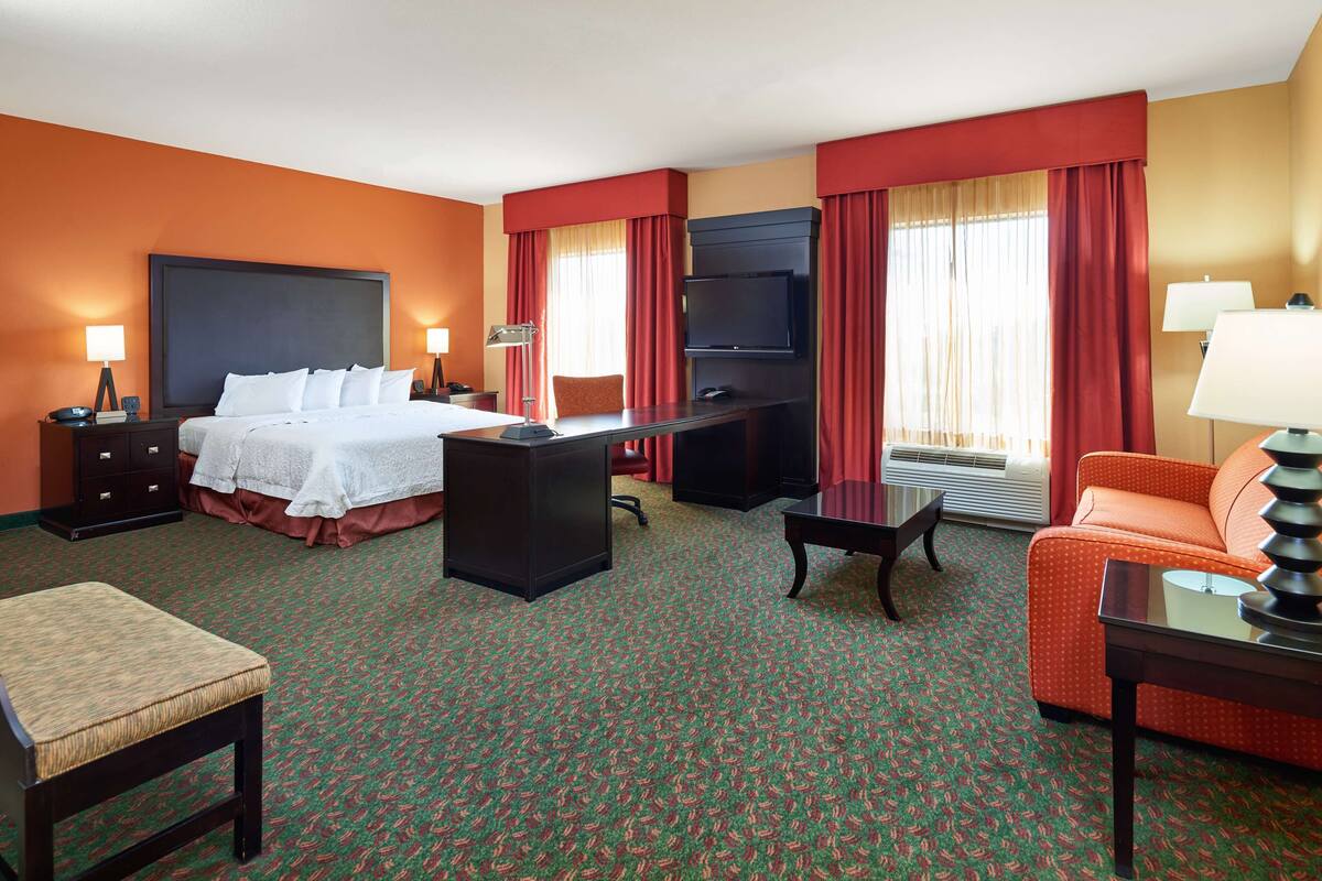 Une chambre d’hôtel équipée d’un lit, d’un bureau, d’une télévision et d’un coin salon.
