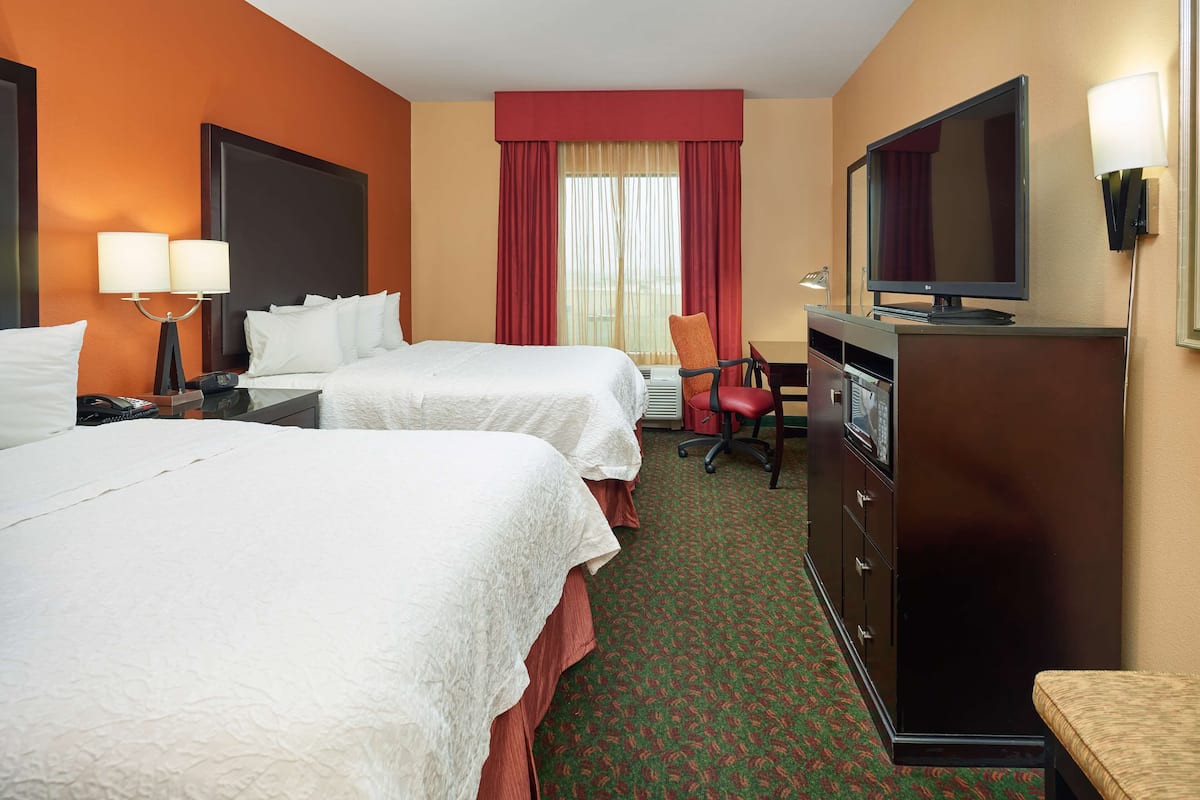 Une chambre d’hôtel avec deux lits, une télévision, un bureau et une chaise.