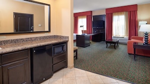 A hotel room with a kitchen area, a seating area with a TV, and a window with curtains. - Hampton Inn & Suites Waco-South (Waco)