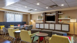 Un hall de hotel con zonas de estar, un televisor y una alfombra estampada.