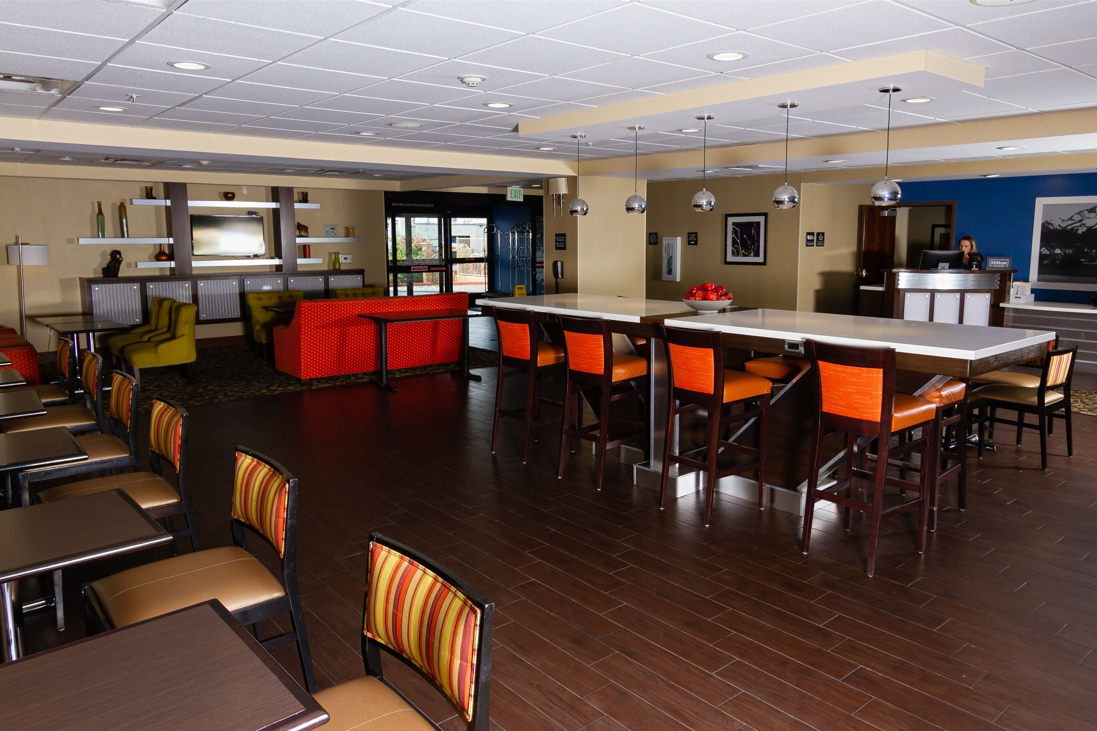 Un amplio vestíbulo de hotel con varias zonas de estar, incluyendo un bar y mesas de comedor.