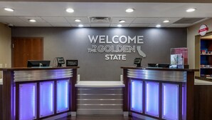 Una mesa de recepción con un cartel que dice "Welcome to the Golden State", un letrero de Hilton Honors y una barra con una computadora y un teléfono.