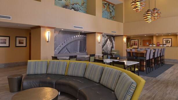 A modern hotel lobby with a curved seating area, a dining area, and artwork on the walls.