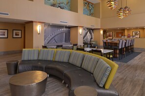Eine moderne Hotelhalle mit einer gebogenen Sitzgruppe, einem Essbereich und Kunstwerken an den Wänden.