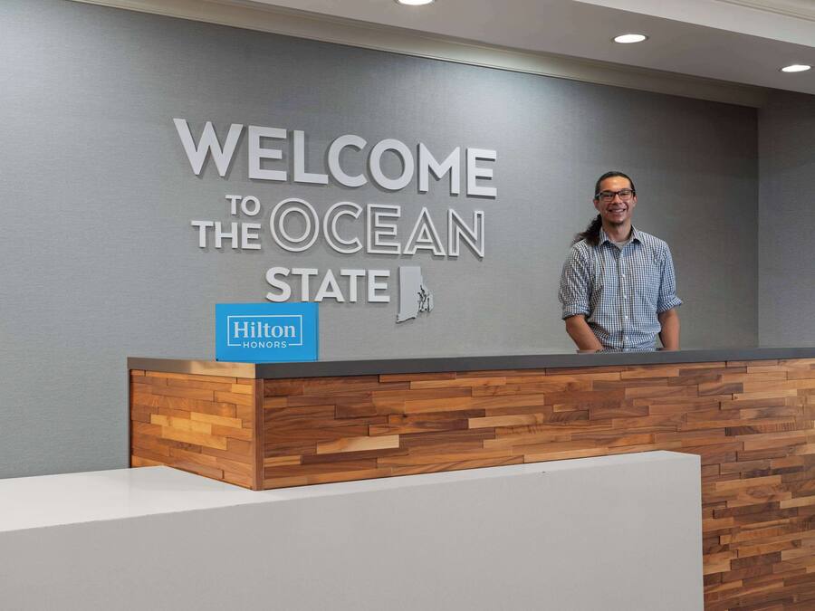 En receptionsdisk med et skilt, der siger "Velkommen til Ocean State", og Hilton-logo.