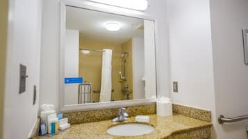 A bathroom with a granite countertop, a sink, a mirror, a towel rack, and a shower visible in the reflection.