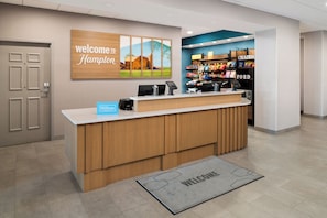 A reception desk with a 'Welcome to Hampton' sign, a 'Hilton' sign, and a 'Chadds Ford' sign. - Hampton Inn & Suites Chadds Ford (Glen Mills)
