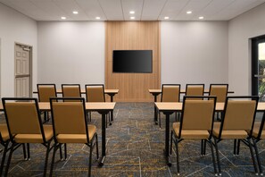 A conference room with a large flat-screen TV, beige chairs, and a patterned carpet. - Hampton Inn & Suites Chadds Ford (Glen Mills)