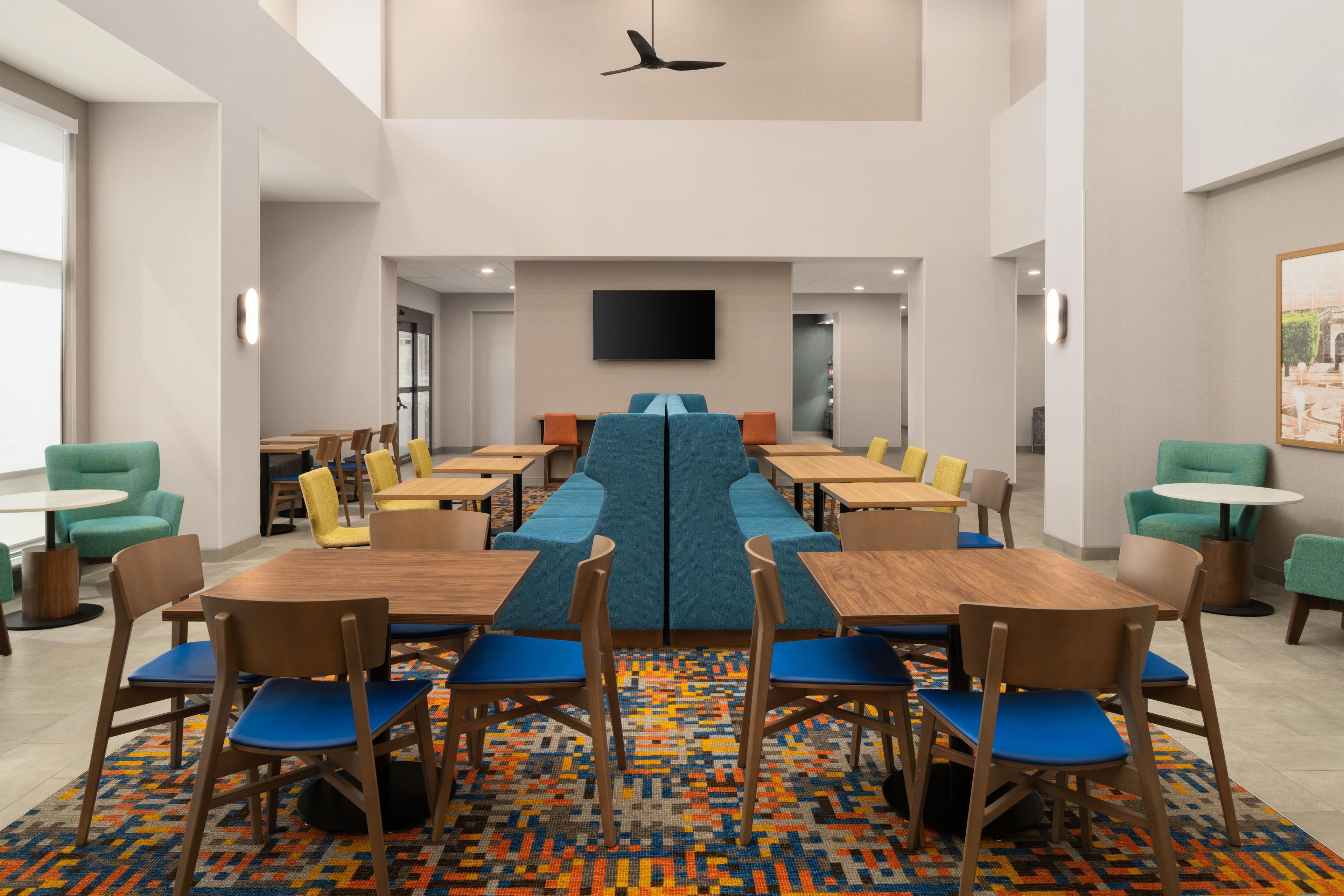 A modern dining area with high tables, chairs, and a central blue bench.
