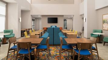 A modern dining area with high tables, chairs, and a central blue bench.