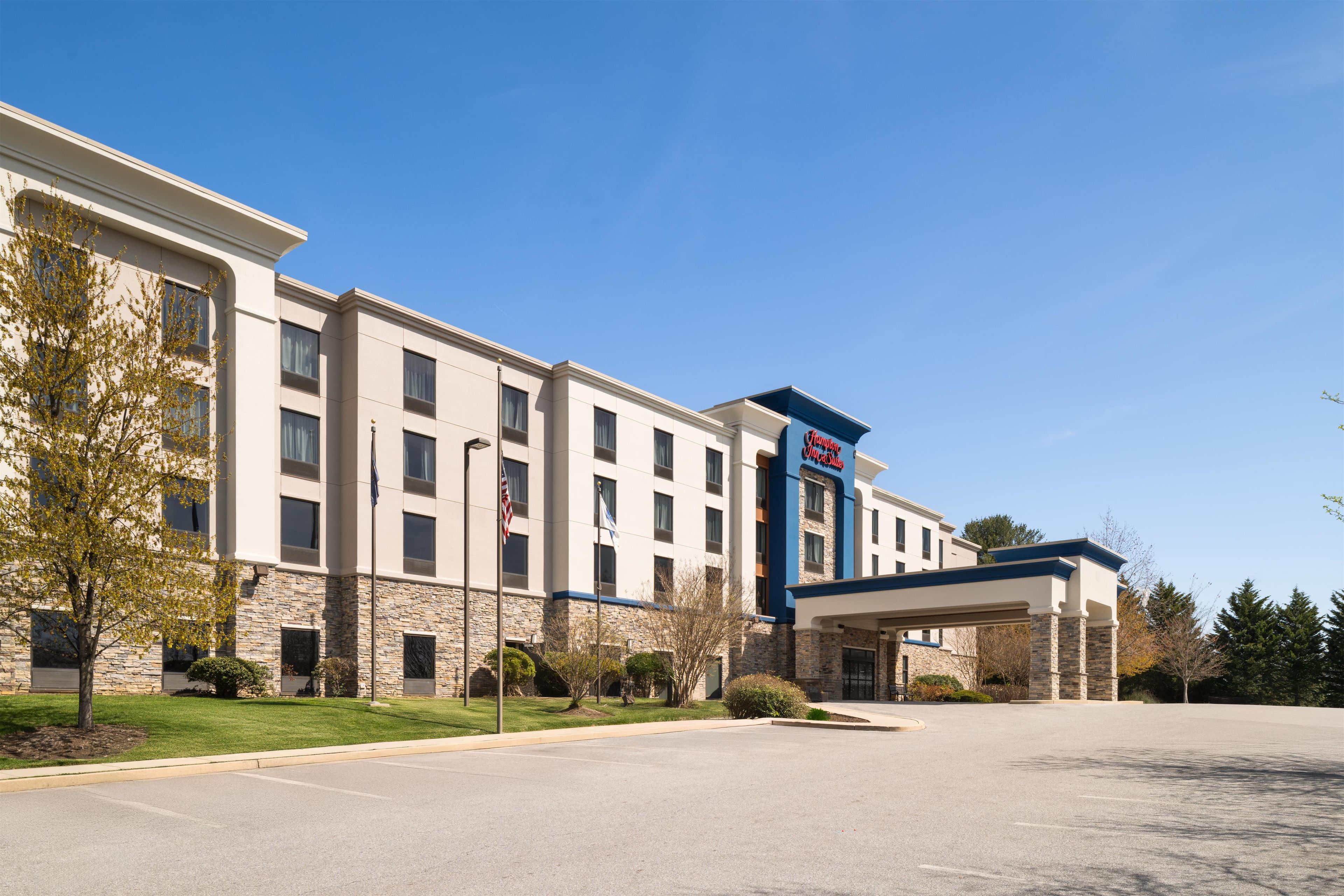 A hotel with a stone facade, a blue and white color scheme, and a parking lot.