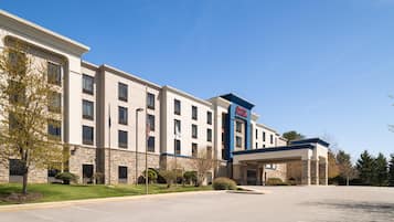 A hotel with a stone facade, a blue and white color scheme, and a parking lot.