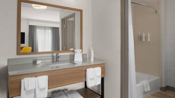 Un baño moderno con tocador de madera, un espejo grande, una bañera y una zona de ducha.
