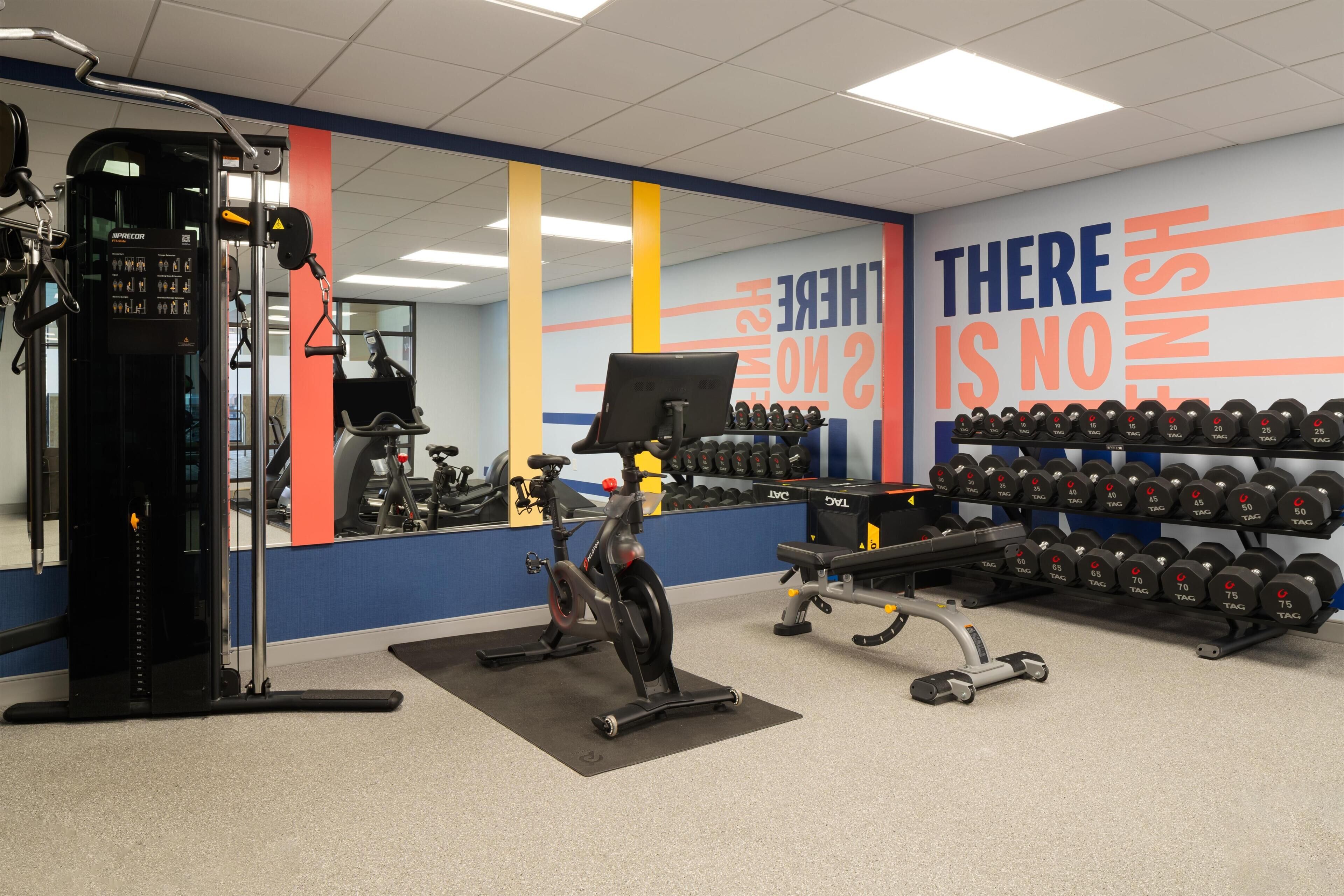 A gym with exercise equipment, a mirror, and motivational wall text.