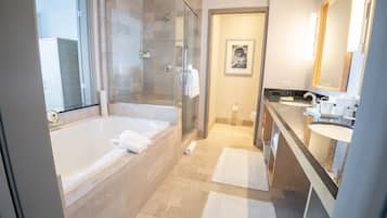 Un baño moderno con ducha envuelta en vidrio, bañera separada y tocador con lavamanos y espejo.