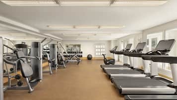 A gym with treadmills, weight machines, and dumbbells.