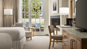 A hotel room with a bed, a desk, a chair, a fireplace, and a large window with curtains. - InterContinental the Clement Monterey by IHG (Monterey)