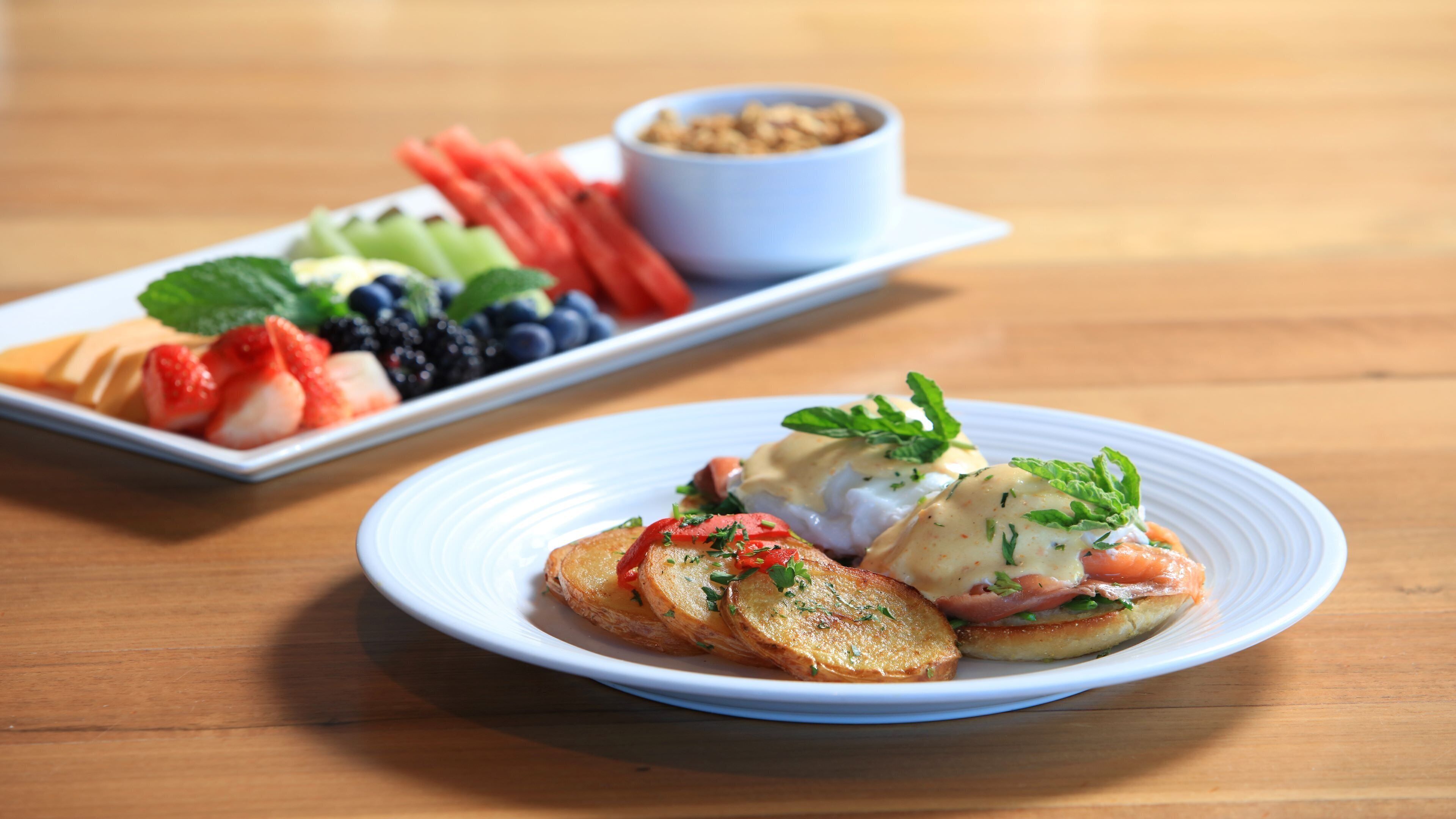 A plate of food with eggs benedict and a side salad.