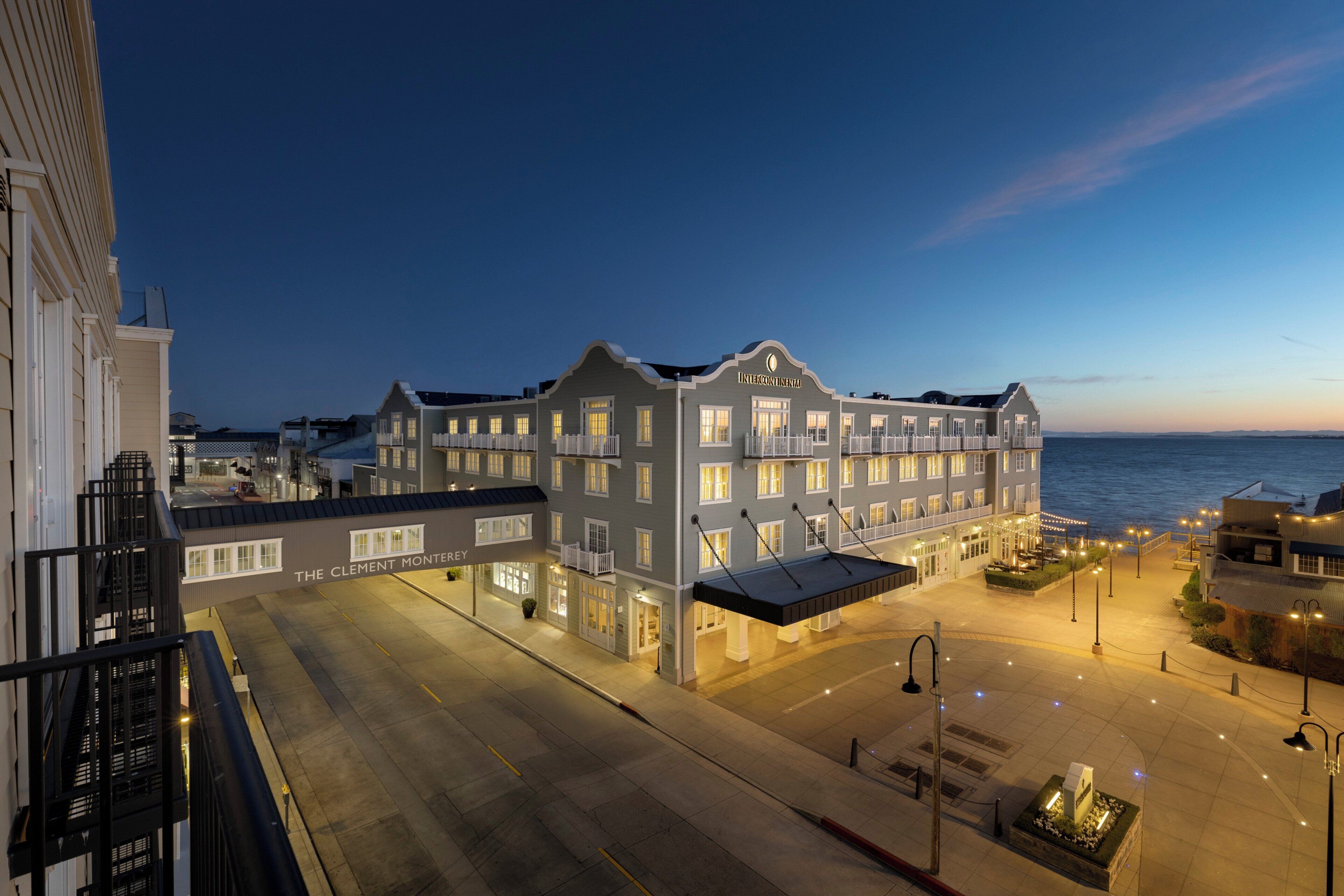A waterfront hotel with a large building, multiple balconies, and a view of the sea.