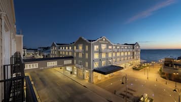 A waterfront hotel with a large building, multiple balconies, and a view of the sea.