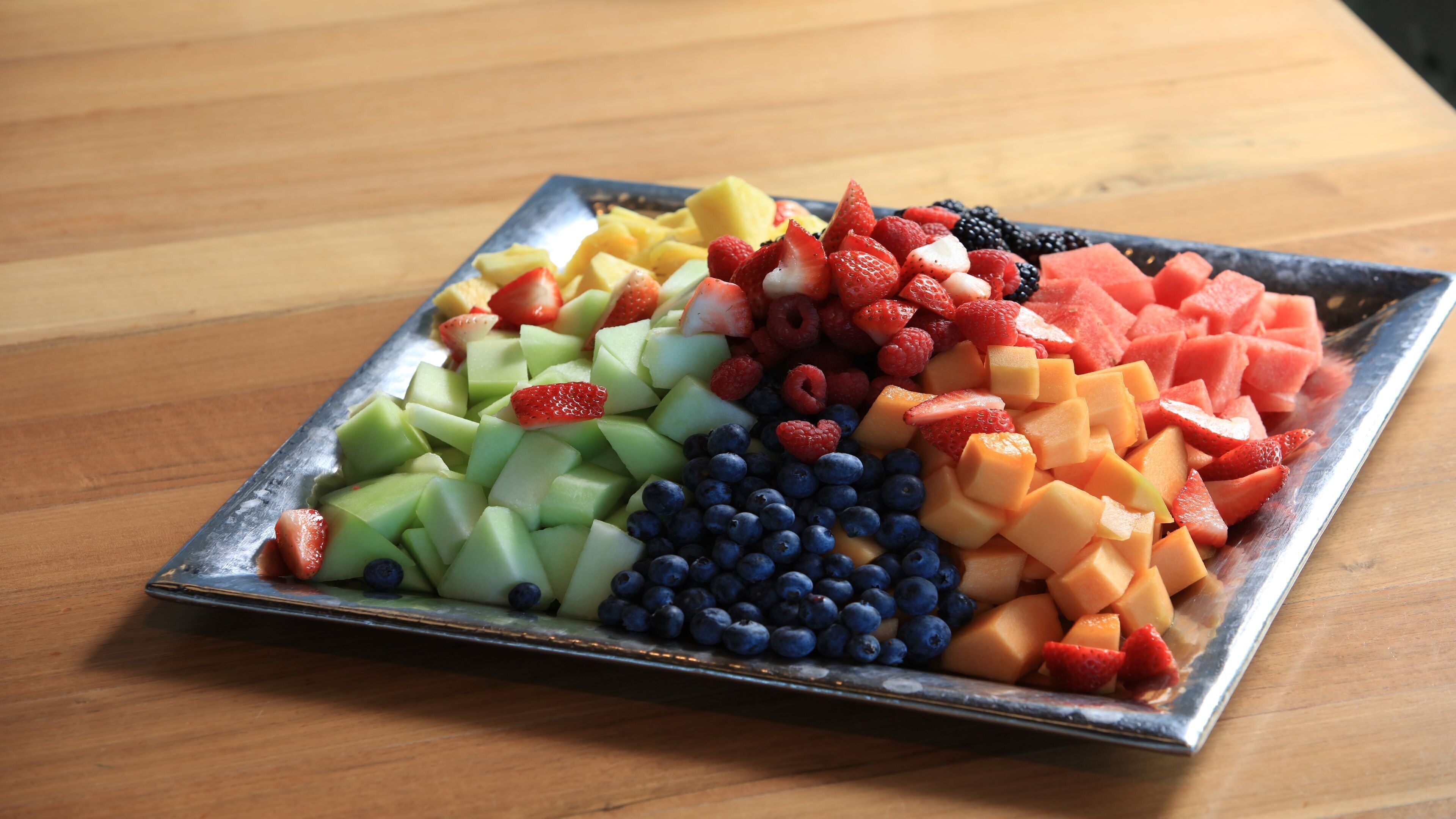 A tray of assorted fruits on a wooden table.