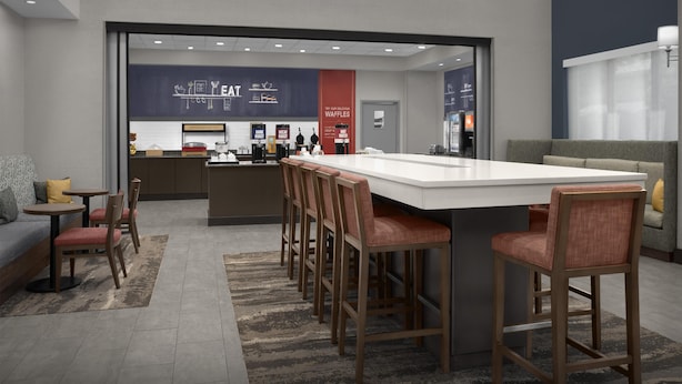 Un área de cocina moderna con una isla central, taburetes de bar y una zona de estar con sofá y sillas.