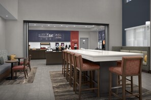 Un área de cocina moderna con una isla central, taburetes de bar y una zona de estar con sofá y sillas.