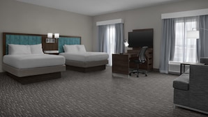 Habitación de hotel con dos camas, un escritorio, una silla, un televisor y un sofá.