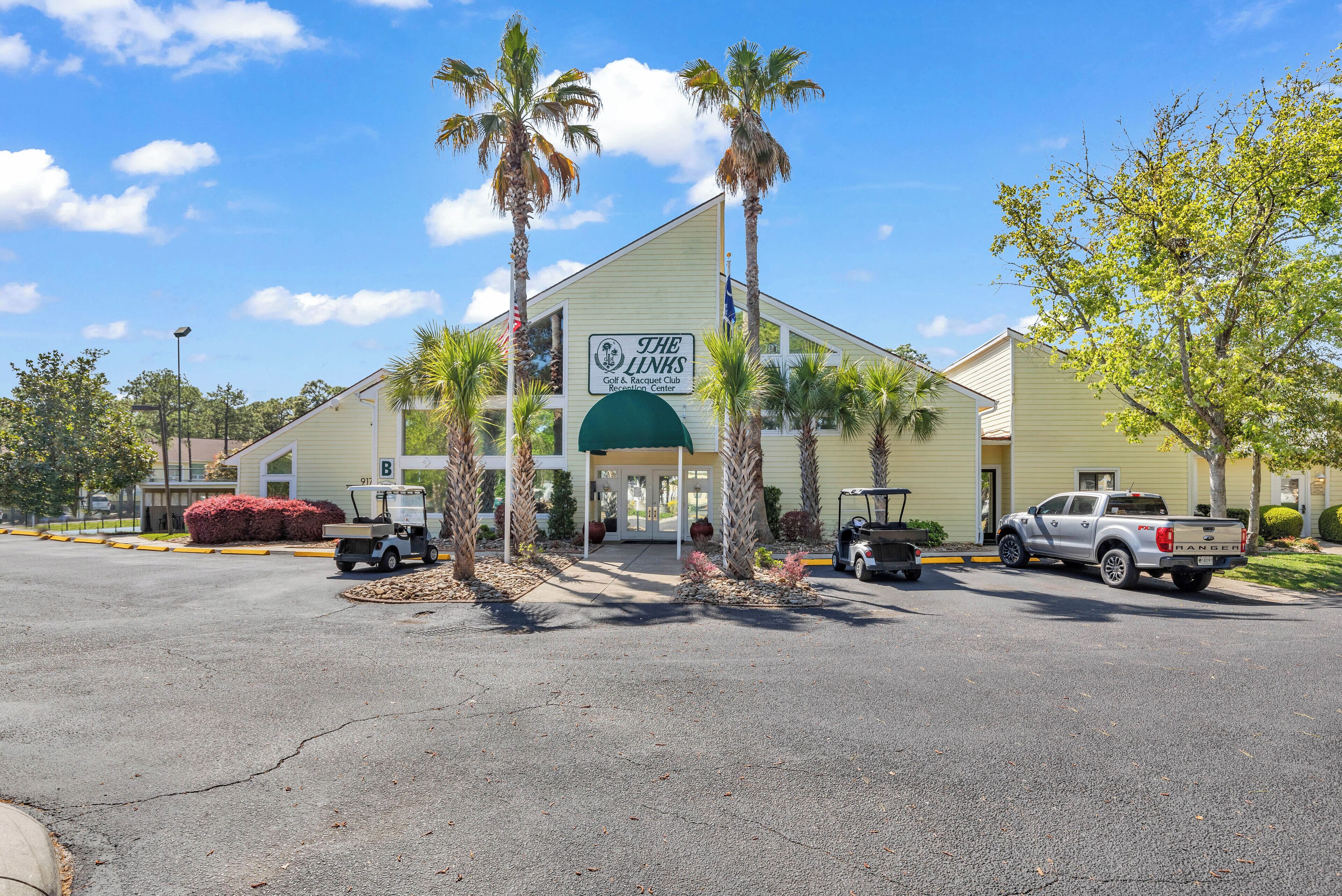 A building with a sign for 'The Links Golf & Country Club' and a parking lot with several vehicles.