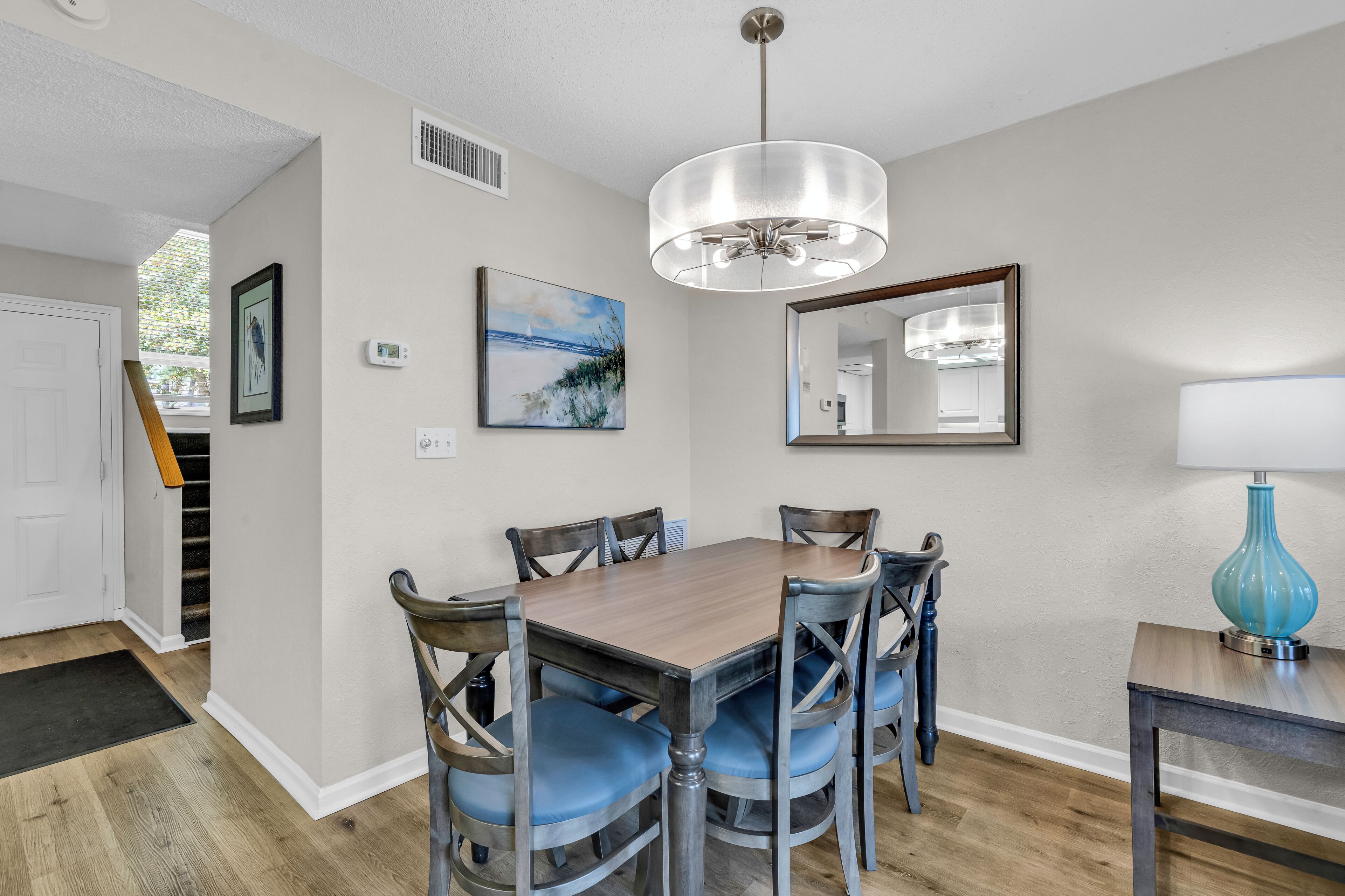 A dining area with a wooden table and chairs, a chandelier, a mirror, and artwork on the walls.