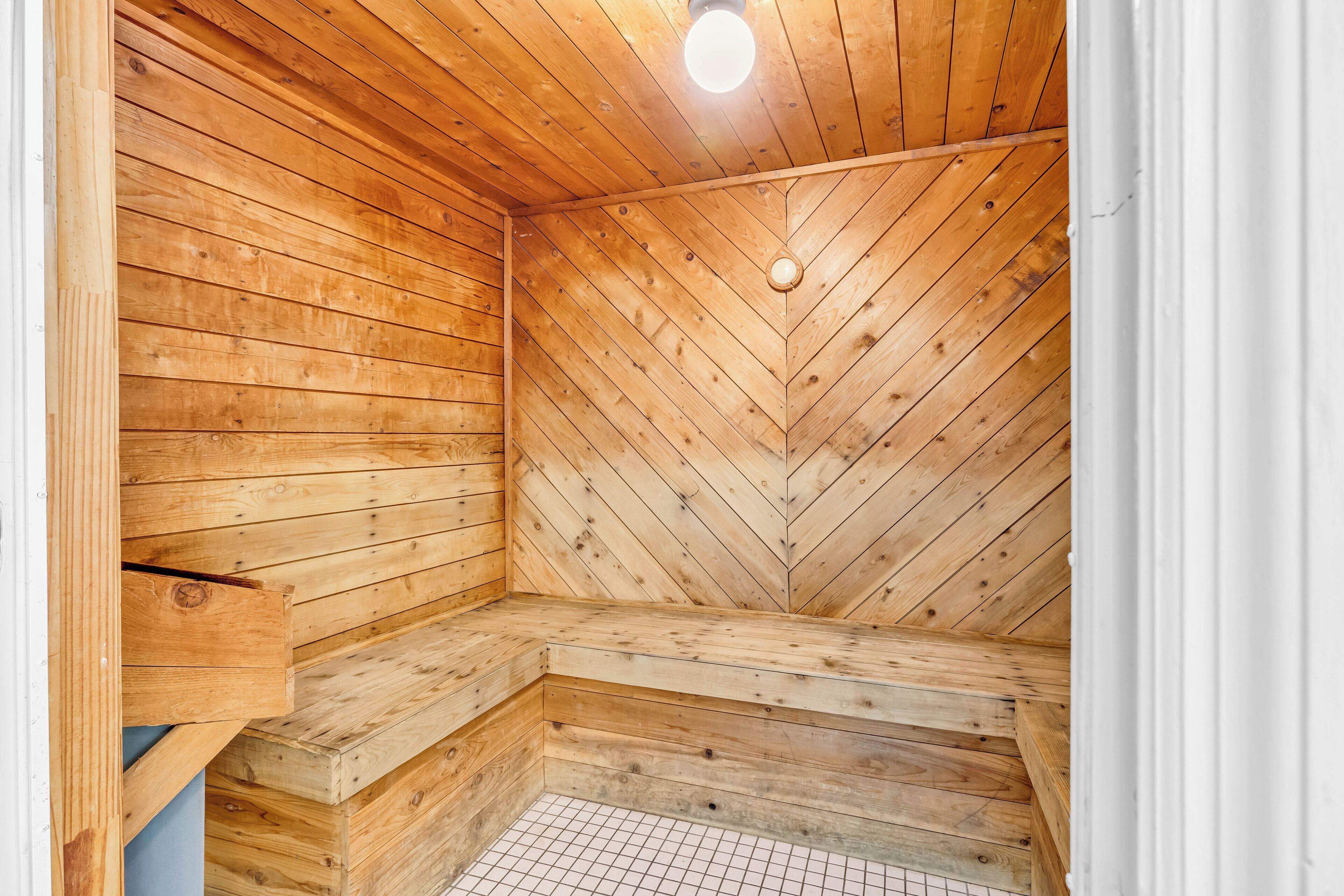 A wooden sauna with a sloped ceiling and a bench.