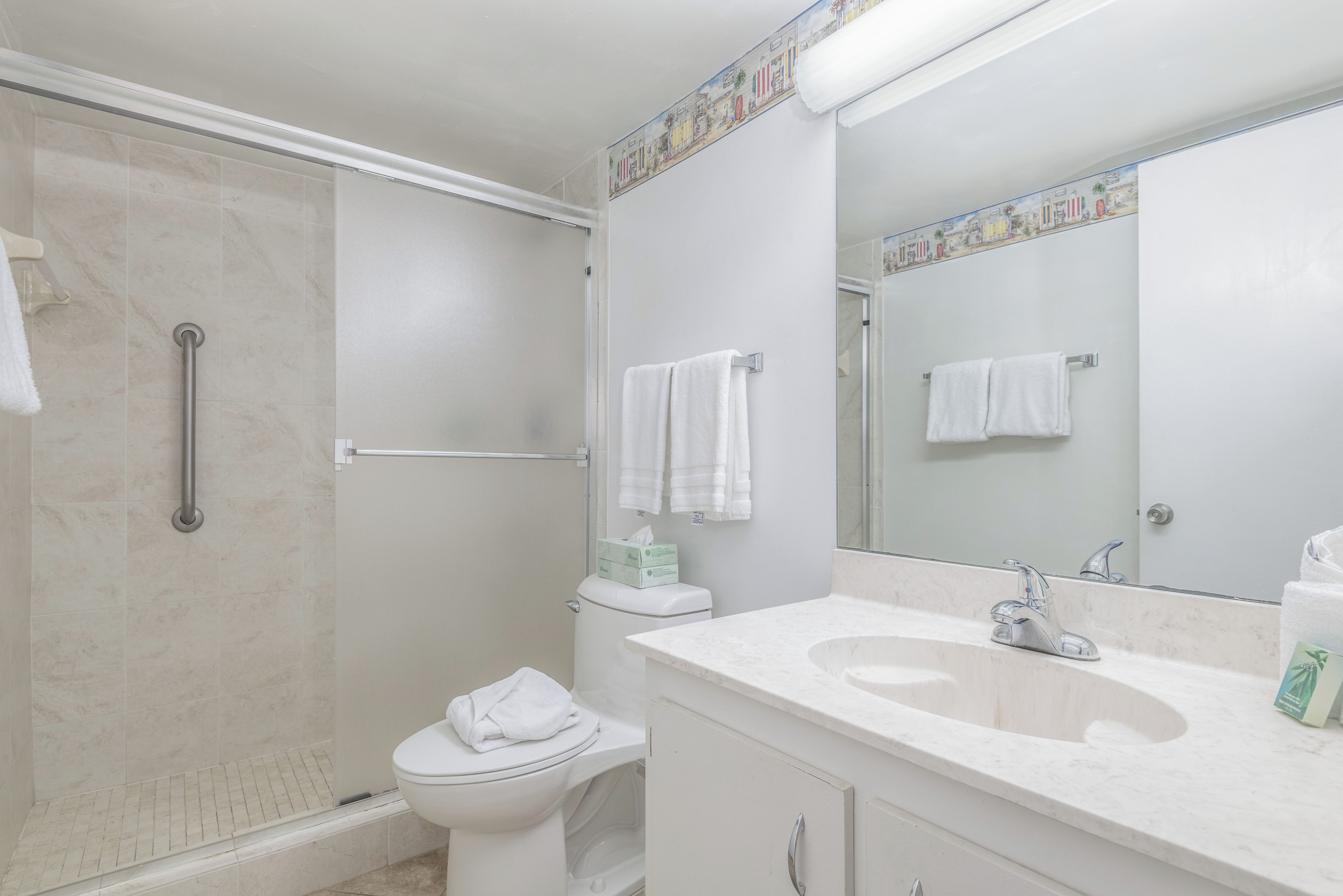 Een badkamer met douche, toilet, wastafel en een grote spiegel.
