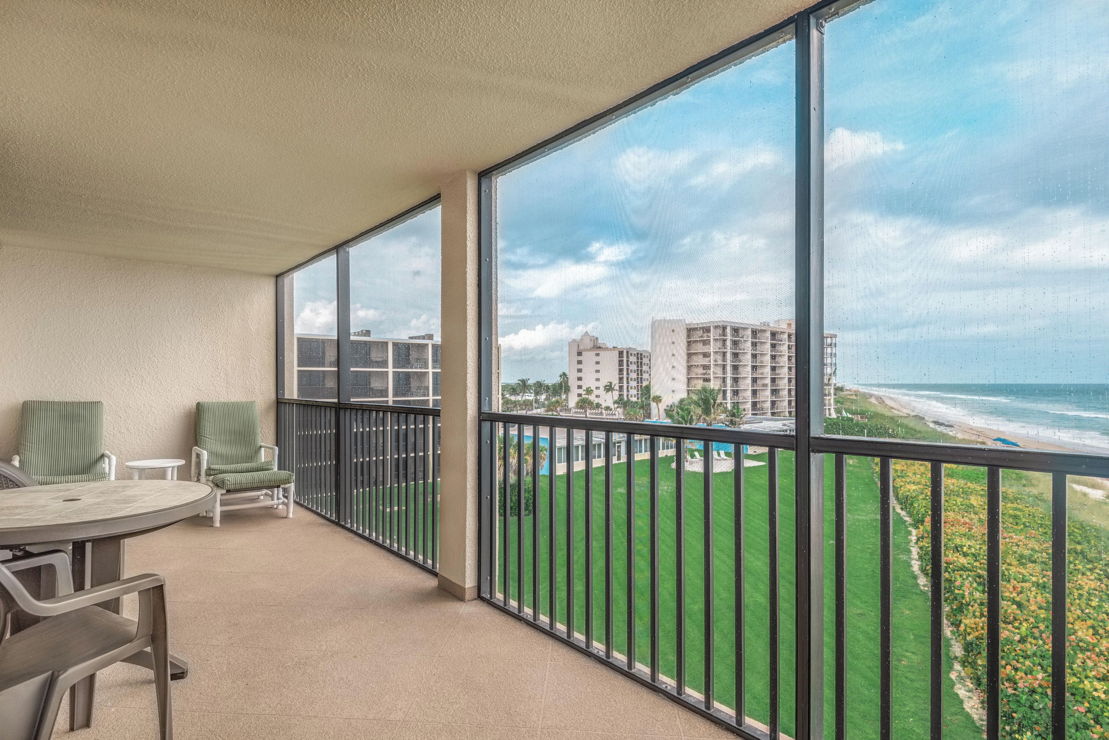 Un balcon avec vue sur une plage et des immeubles.