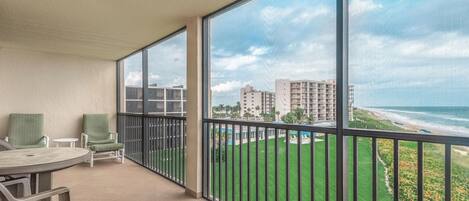 Un balcon avec vue sur une plage et des immeubles.