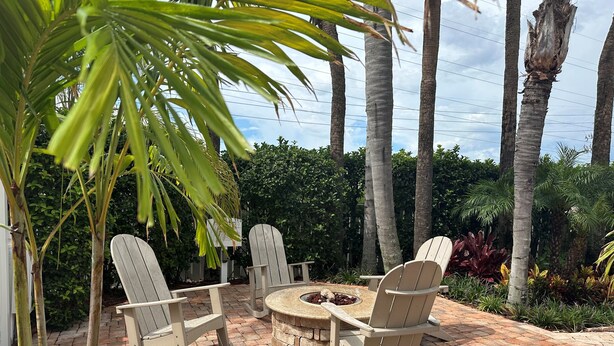 A patio with Adirondack chairs and a round table, surrounded by palm trees and a brick floor. - Bluegreen Vacations Orlando's Sunshine, Ascend Collection Resort (Orlando)