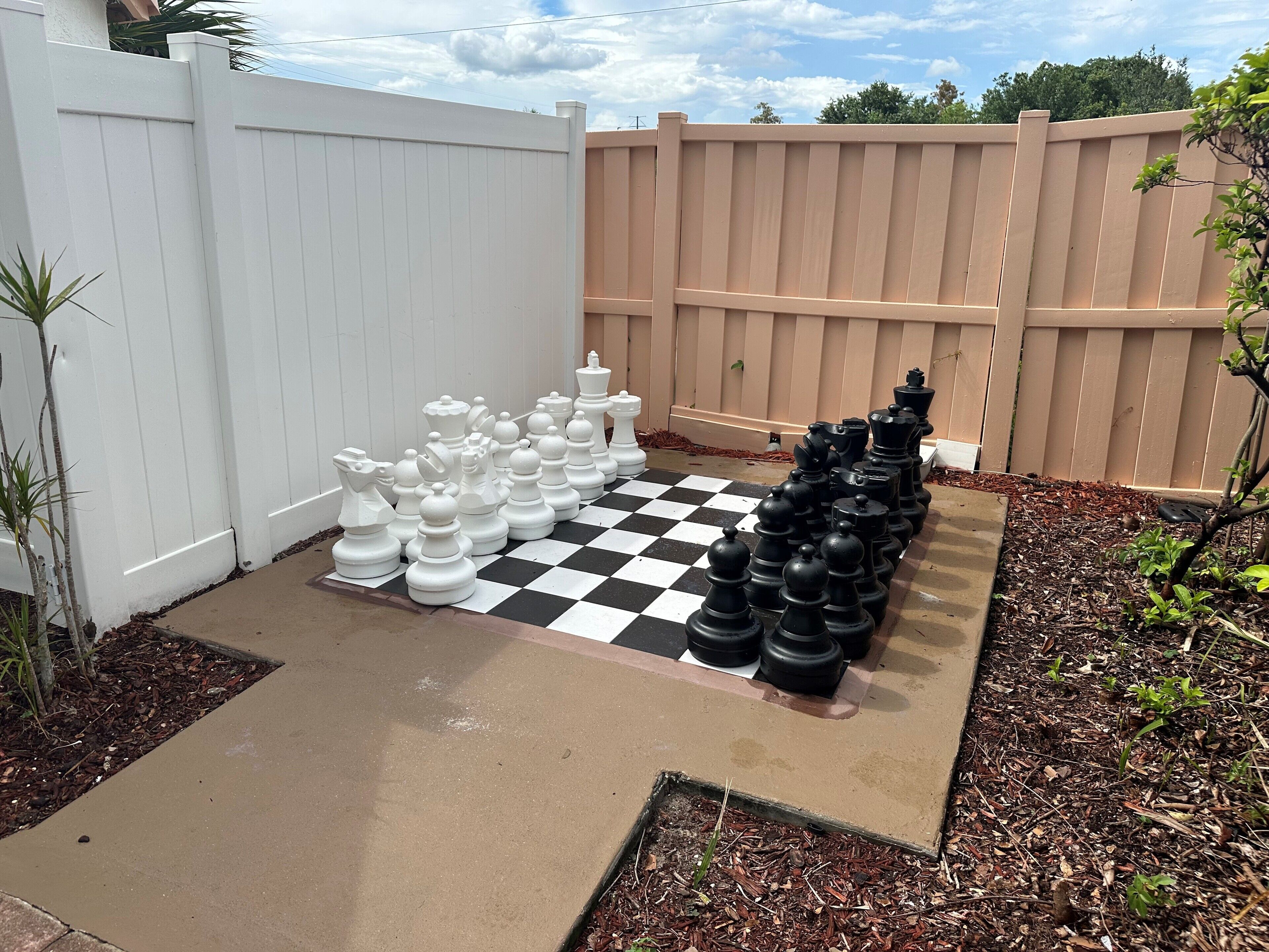 A checkered outdoor area with a white and black chess set.