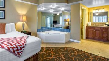 A hotel room with a bed, a bathroom with a bathtub, and a separate bathroom with a sink and mirror.