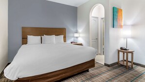 Ein Hotelzimmer mit einem großen Bett, einem Nachttisch, einer Lampe und einem Gemälde an der Wand.