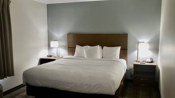A hotel room with a large bed, two bedside tables with lamps, a heater, and a telephone.
