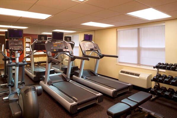 Un gimnasio con cintas de correr, pesas y bancos.