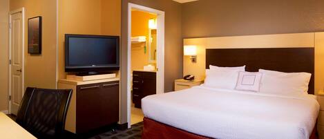 Una habitación de hotel con una cama, televisor, escritorio y una silla.
