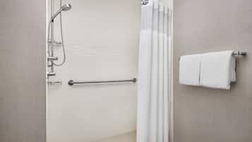 A modern bathroom with a shower, a handrail, a towel rack, and a textured wall.