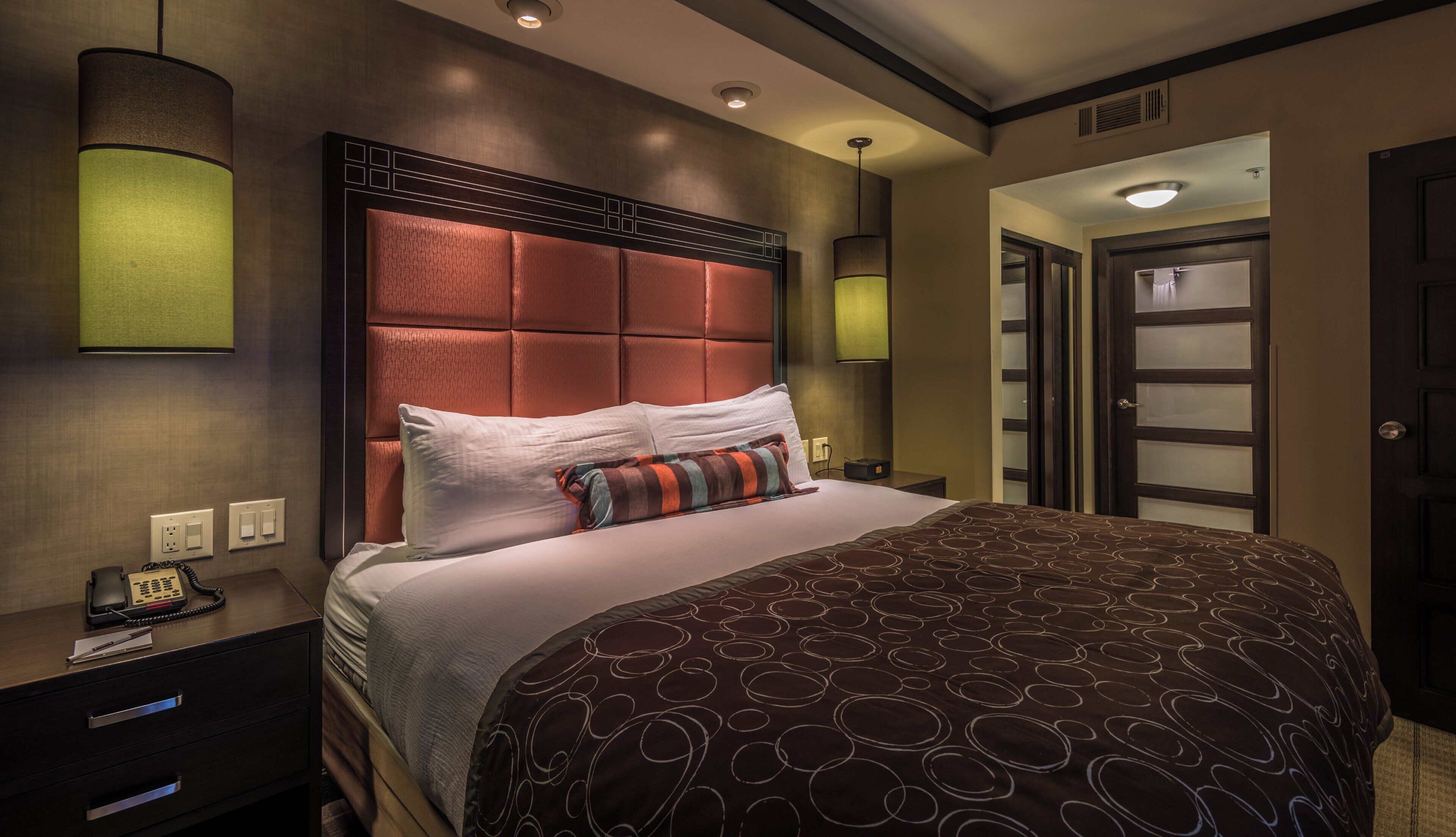 A hotel room with a large bed, a bedside telephone, and a nightstand.