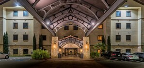 A hotel entrance with a stone facade, arched roof, and multiple windows.