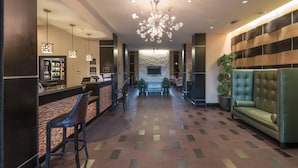 A hotel lobby with a reception desk, bar area, and seating. - Staybridge Suites DFW Airport North by IHG (Irving)