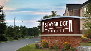 A sign for Staybridge Suites with a brick base and a curved top.