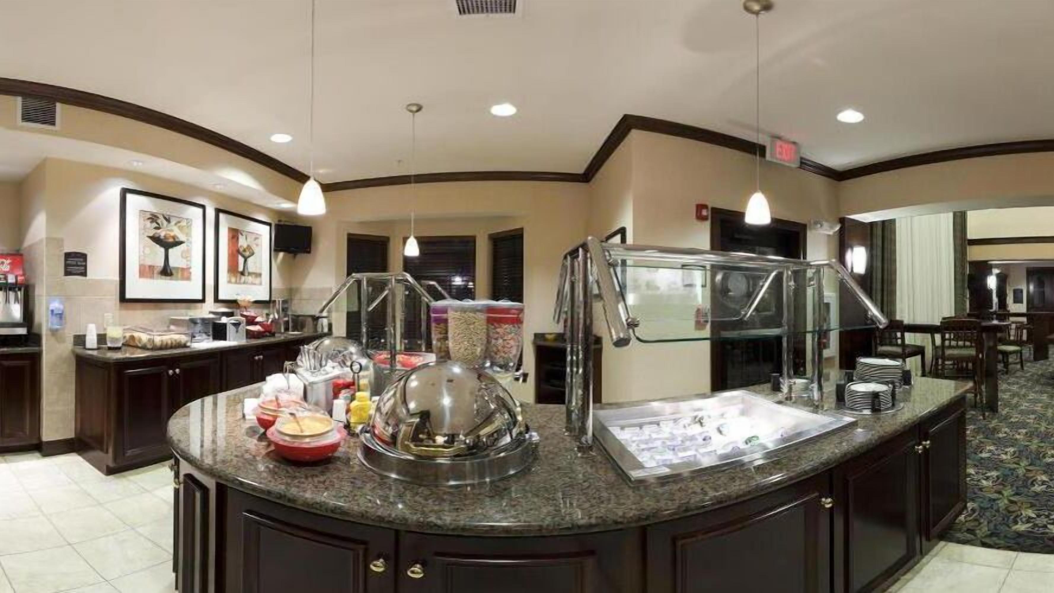 A buffet area with a marble counter, food containers, and a glass display case.