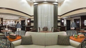 A hotel lobby with a central seating area, a bar, and a dining area. - Staybridge Suites Akron-Stow-Cuyahoga Falls by IHG (Stow)